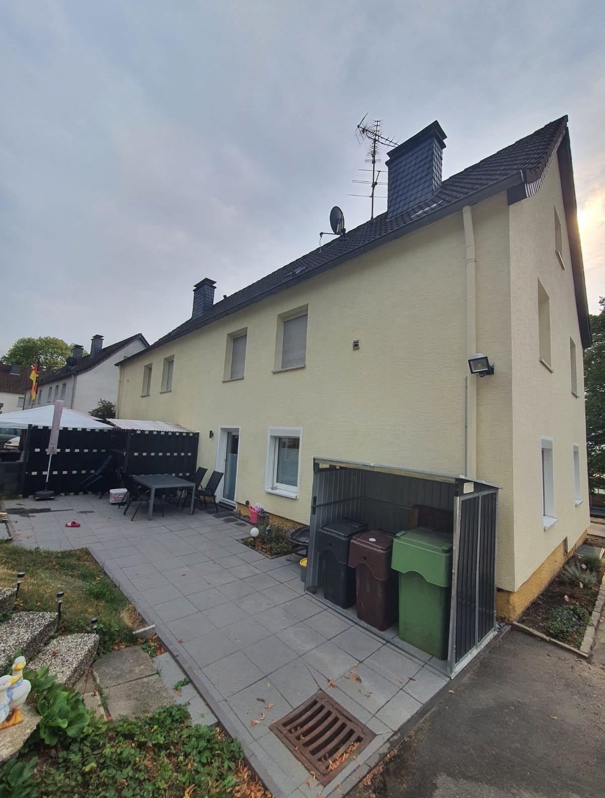 Seitenansicht mit Terrasse und Müllboxen